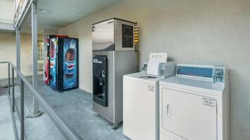 A laundry area with a refrigerator, a vending machine, and a washing machine.