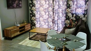 Sala de estar com sofá, mesa de centro e área de jantar com cadeiras e mesa.