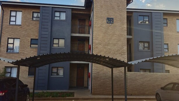Um edifício residencial com vários andares e área de estacionamento coberta.