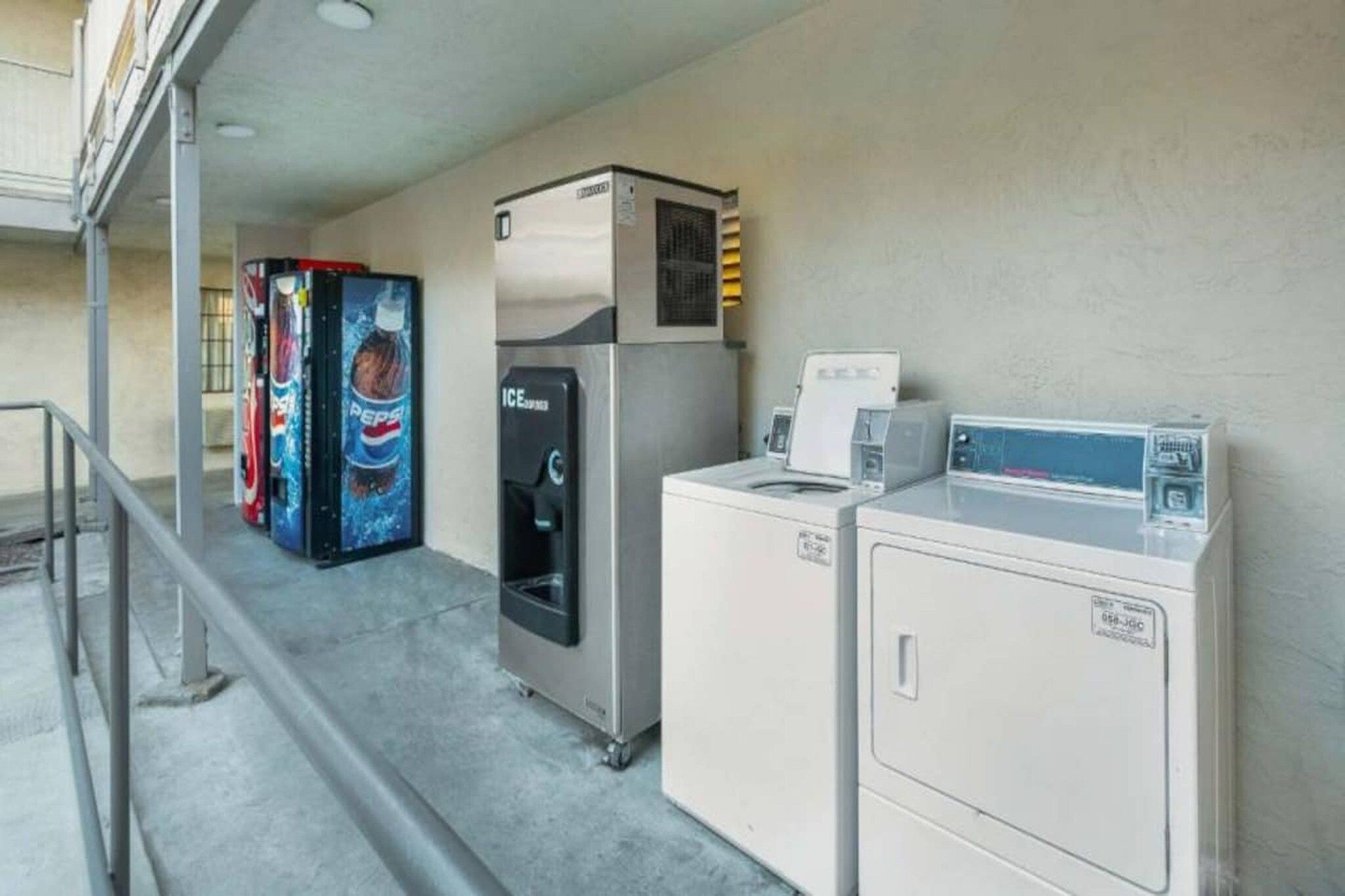 A laundry area with a refrigerator, a vending machine, and a washing machine.