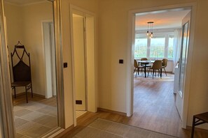 A hallway leading to a dining area with a table and chairs, a hanging chair, and a view through the door. - Near the sea & plenty of sunshine (Cuxhaven)