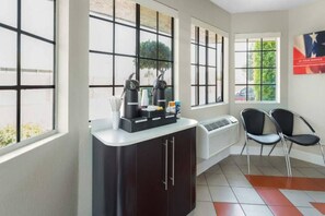 Una habitación con kitchenette, un radiador, un ventanal con vistas a vegetación y una silla.