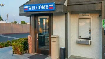 A building with a 'WELCOME' sign, a registration area, and a trash bin outside.