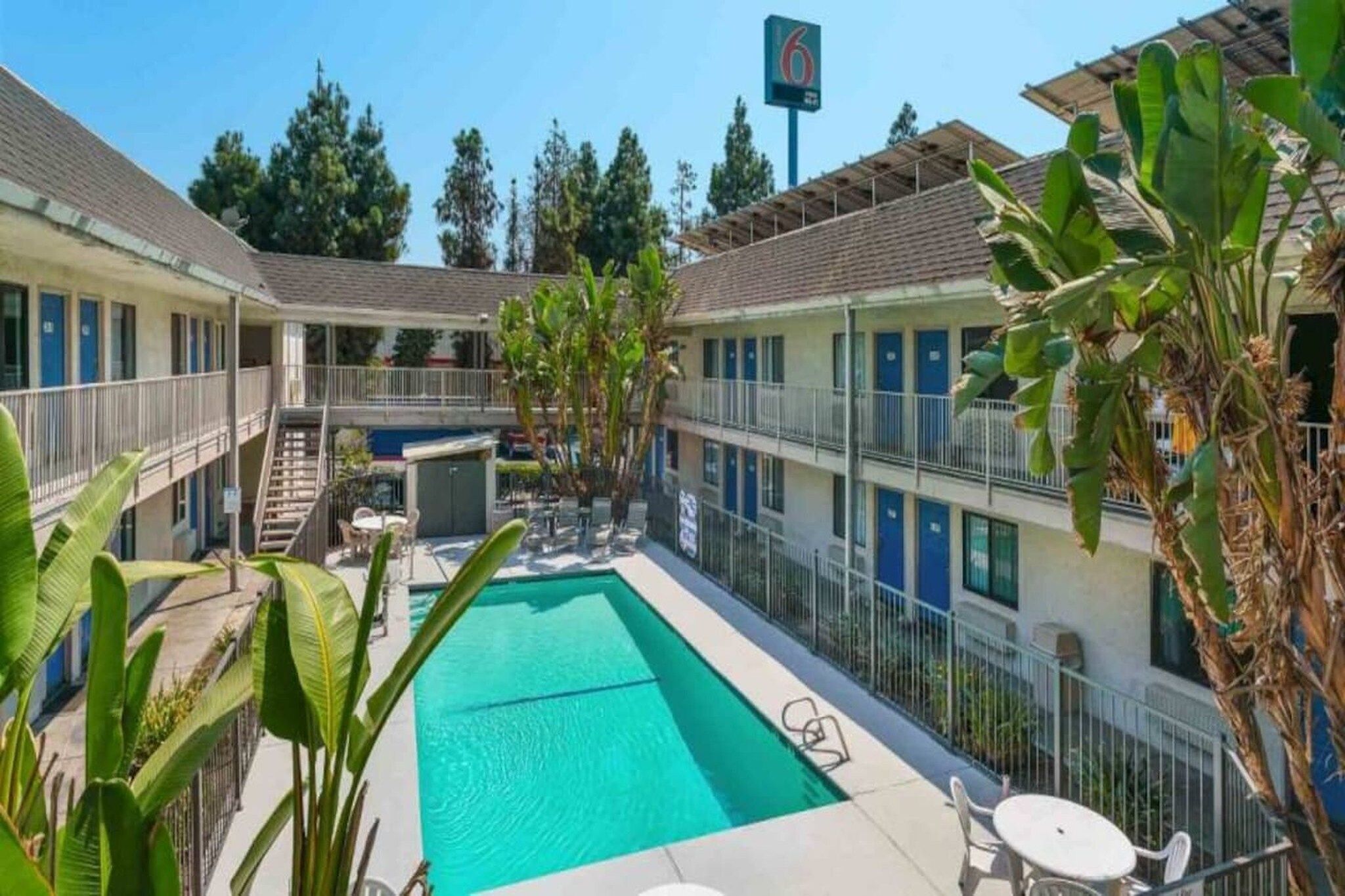 A hotel with a swimming pool, outdoor seating, and a sign indicating the number 6.