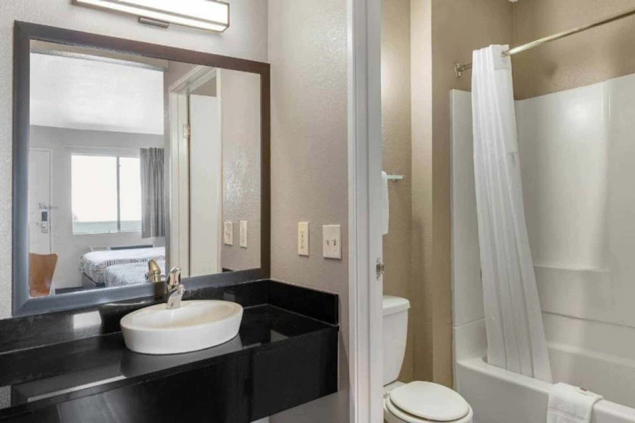 A bathroom with a white sink, a mirror, a toilet, and a shower area.