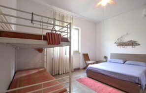 Ein Zimmer mit Etagenbetten, einem Sessel, einem Bett, einem Heizkörper und einer Wanddekoration.