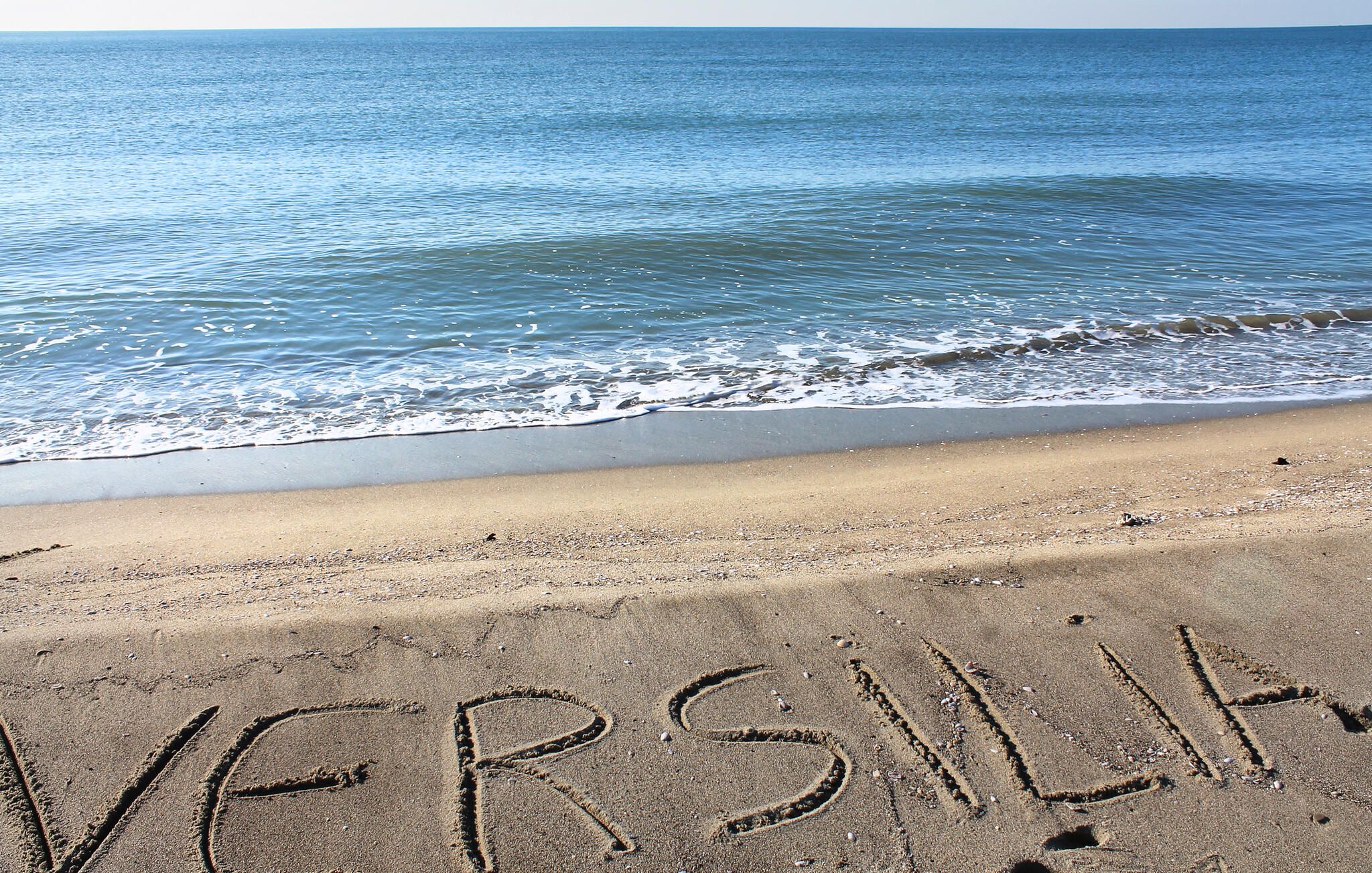 A beach with the word 'VERSILIA' written in the sand.