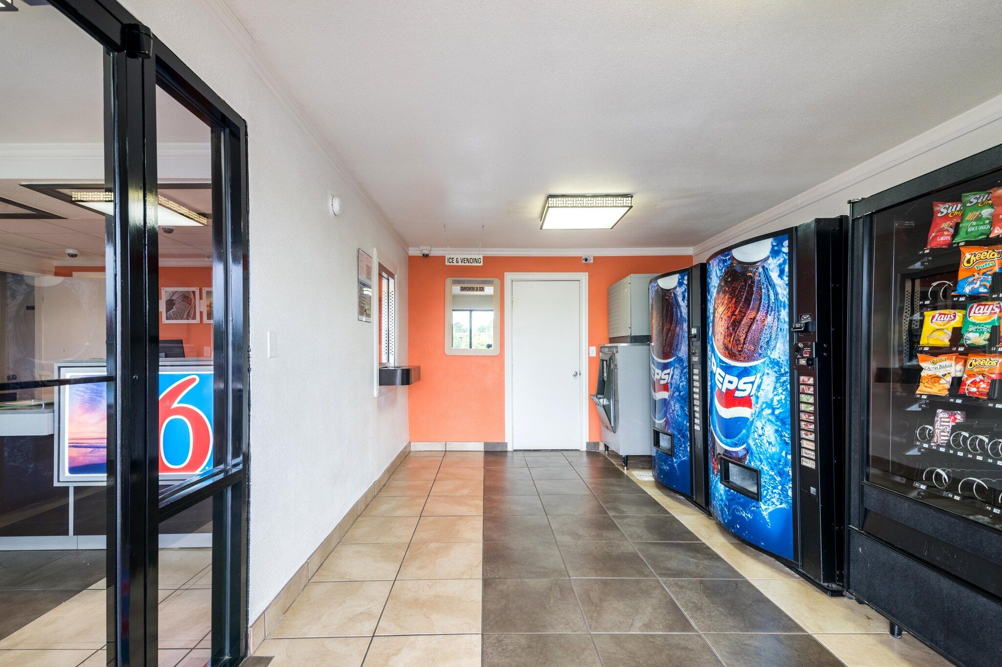 Un pasillo con máquinas expendedoras, una puerta con la leyenda 'Hielo y Vending' y un mostrador con un cartel grande que indica el número '6'.