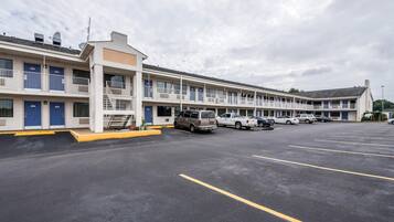 A motel with multiple rooms, a parking lot, and a few vehicles parked.
