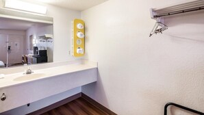 Un baño de hotel con un espejo grande, un lavabo blanco y un perchero para toallas.