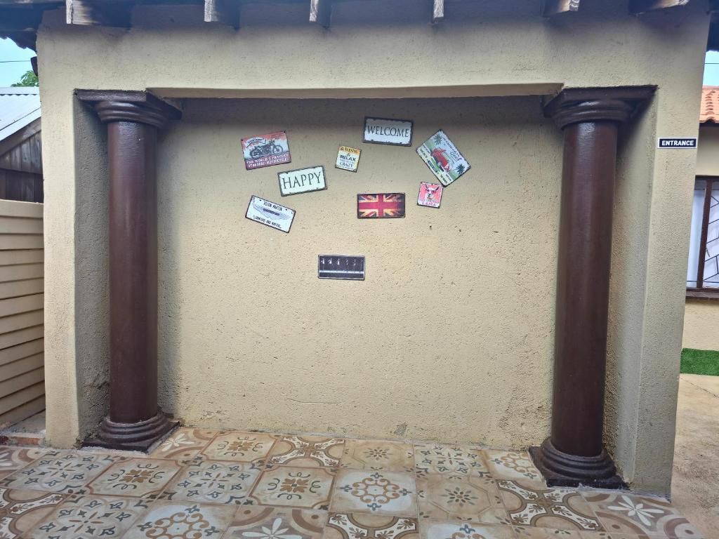 Un mur orné d’une pancarte de bienvenue et de divers autocollants, dont un drapeau, situé sous une structure à colonnes.