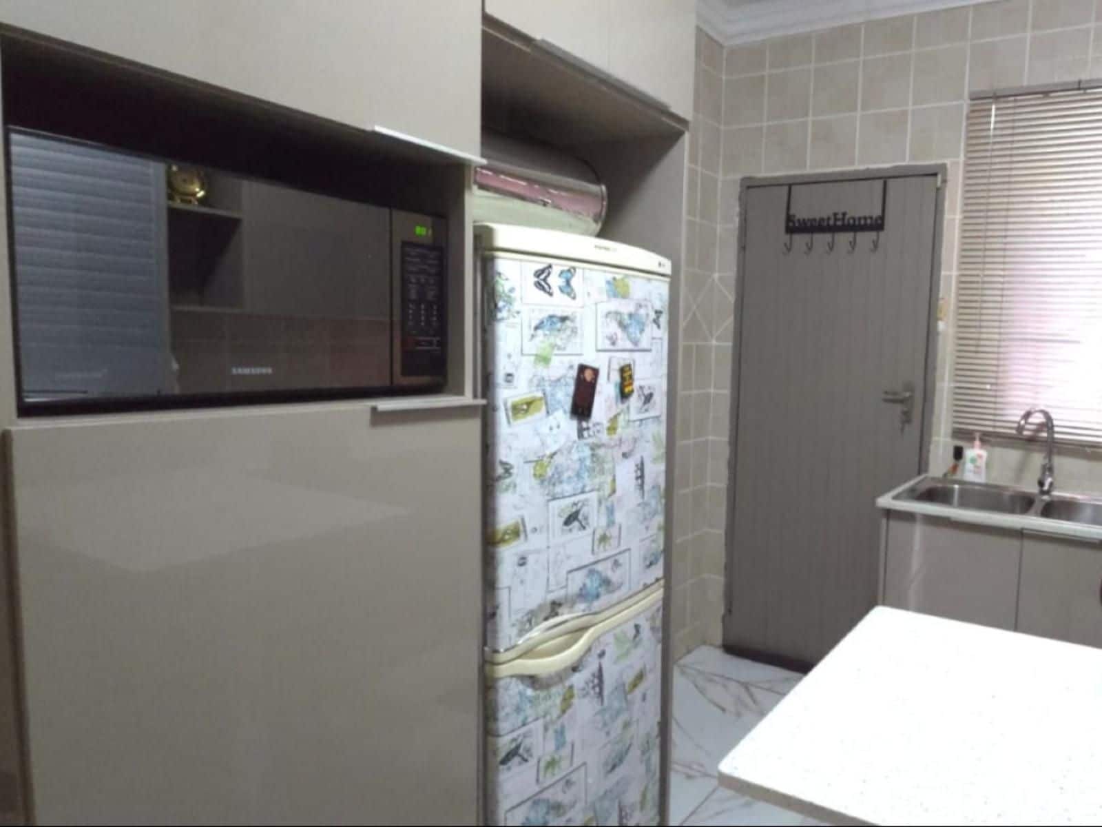 A compact kitchen with a refrigerator, a microwave, and a sink.