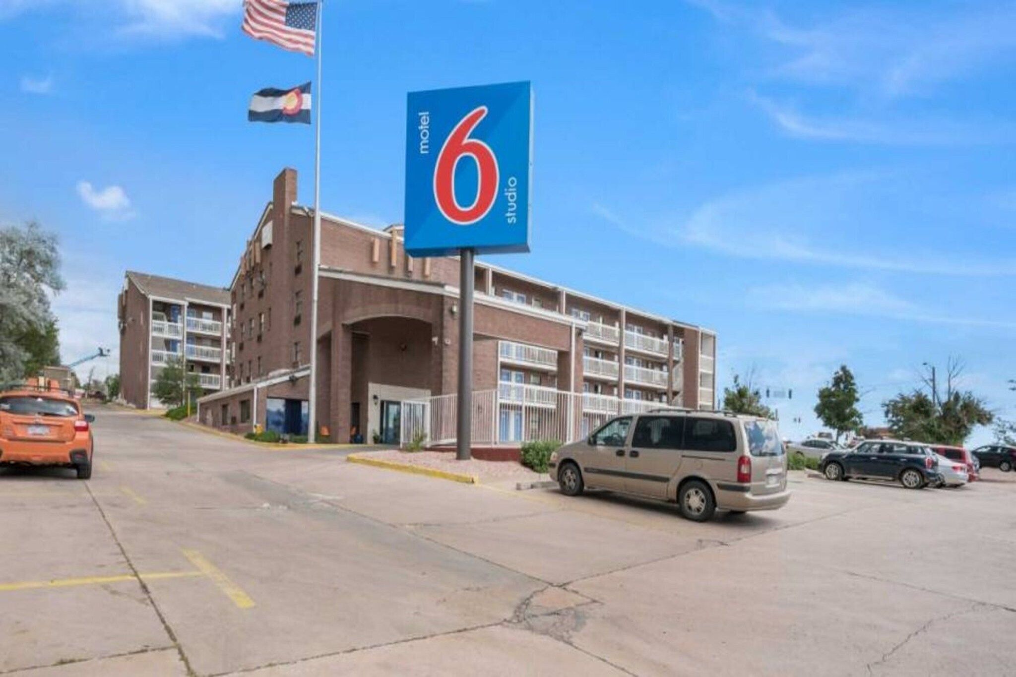 A motel with a large '6' sign, multiple floors, and a parking lot with cars.