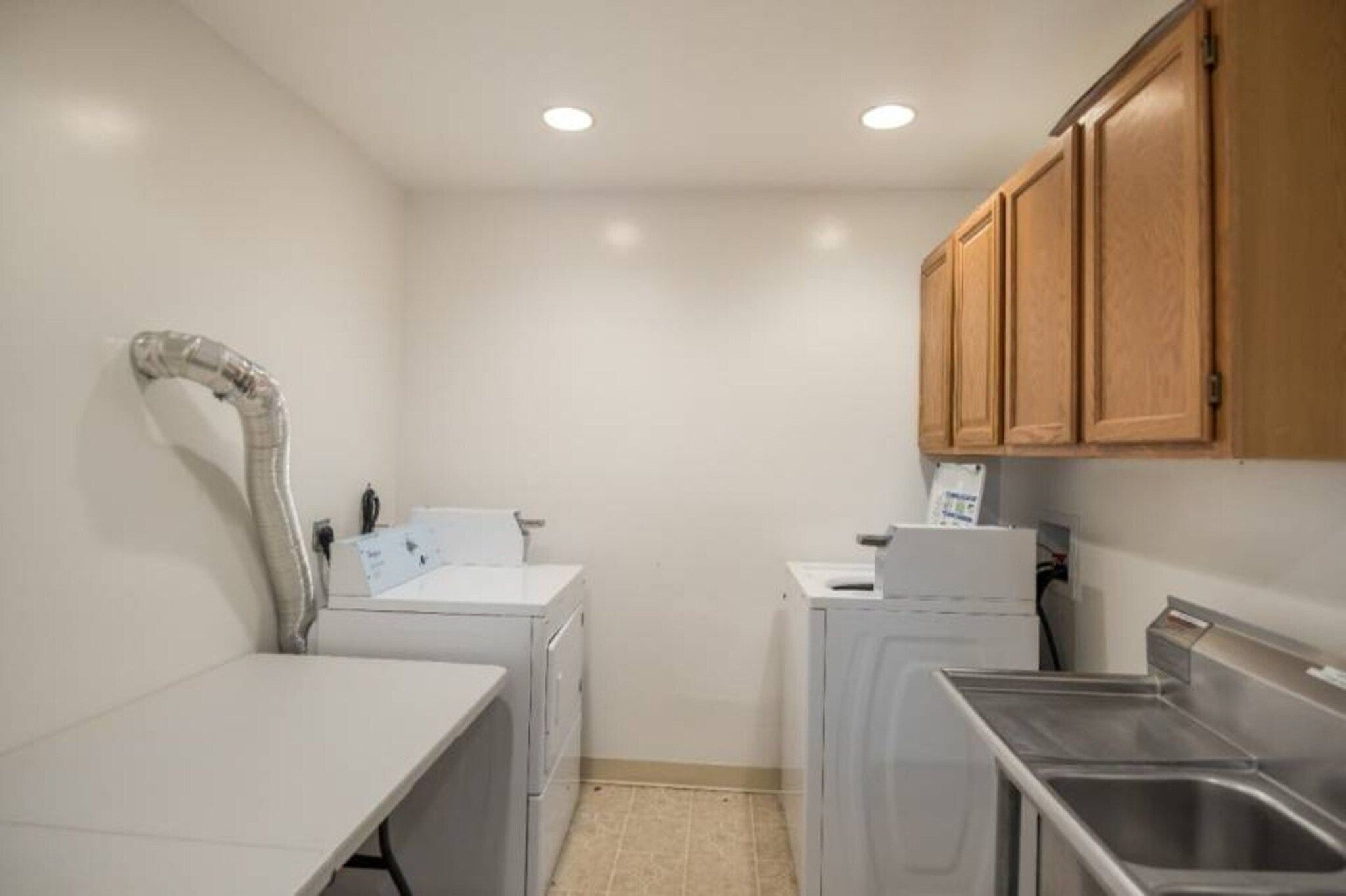 A compact laundry room with a washing machine, dryer, and a small sink.