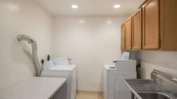 A compact laundry room with a washing machine, dryer, and a small sink.