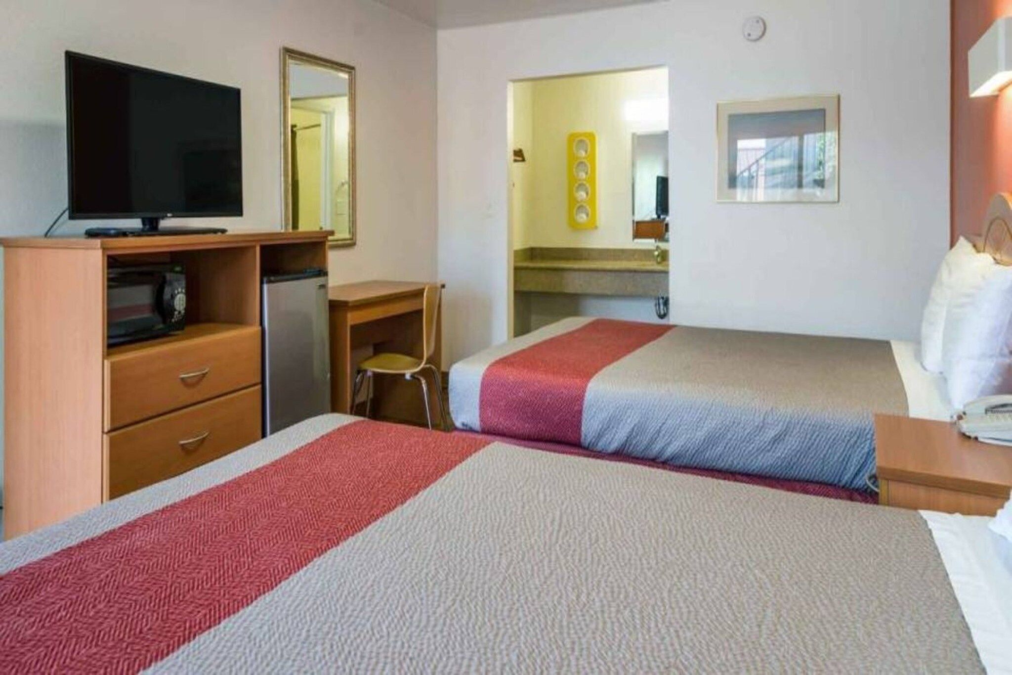 Une chambre d’hôtel avec deux lits, un bureau, une télévision et un miroir.