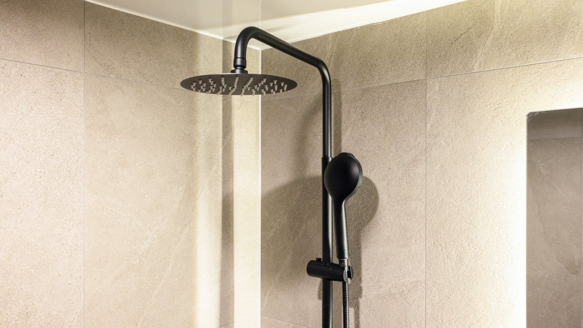 A modern shower with a curved head and a handheld showerhead.