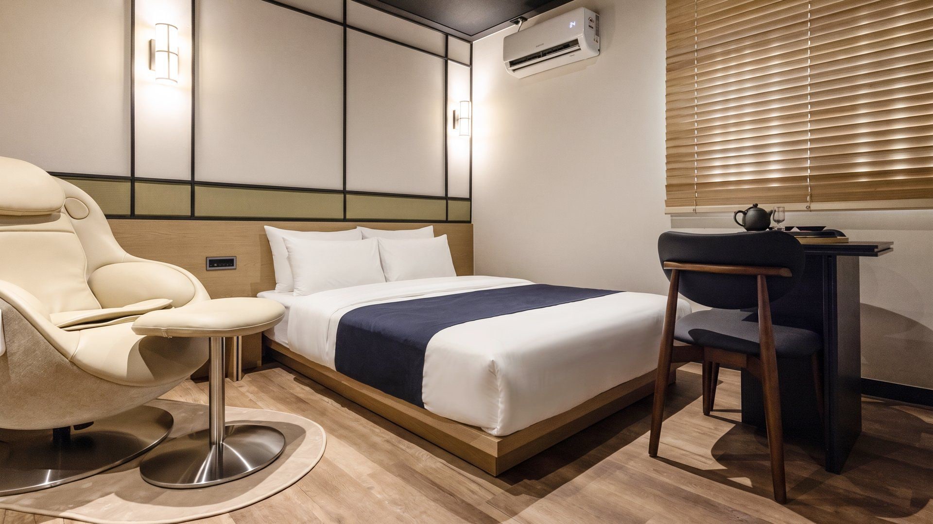 Una habitación de hotel con cama, una silla, un escritorio y un equipo de aire acondicionado.