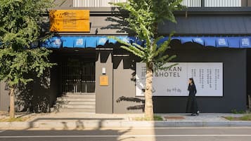 Entrada de un hotel con un cartel que dice 'Ryokan & Hotel' y una persona de pie cerca de la entrada.