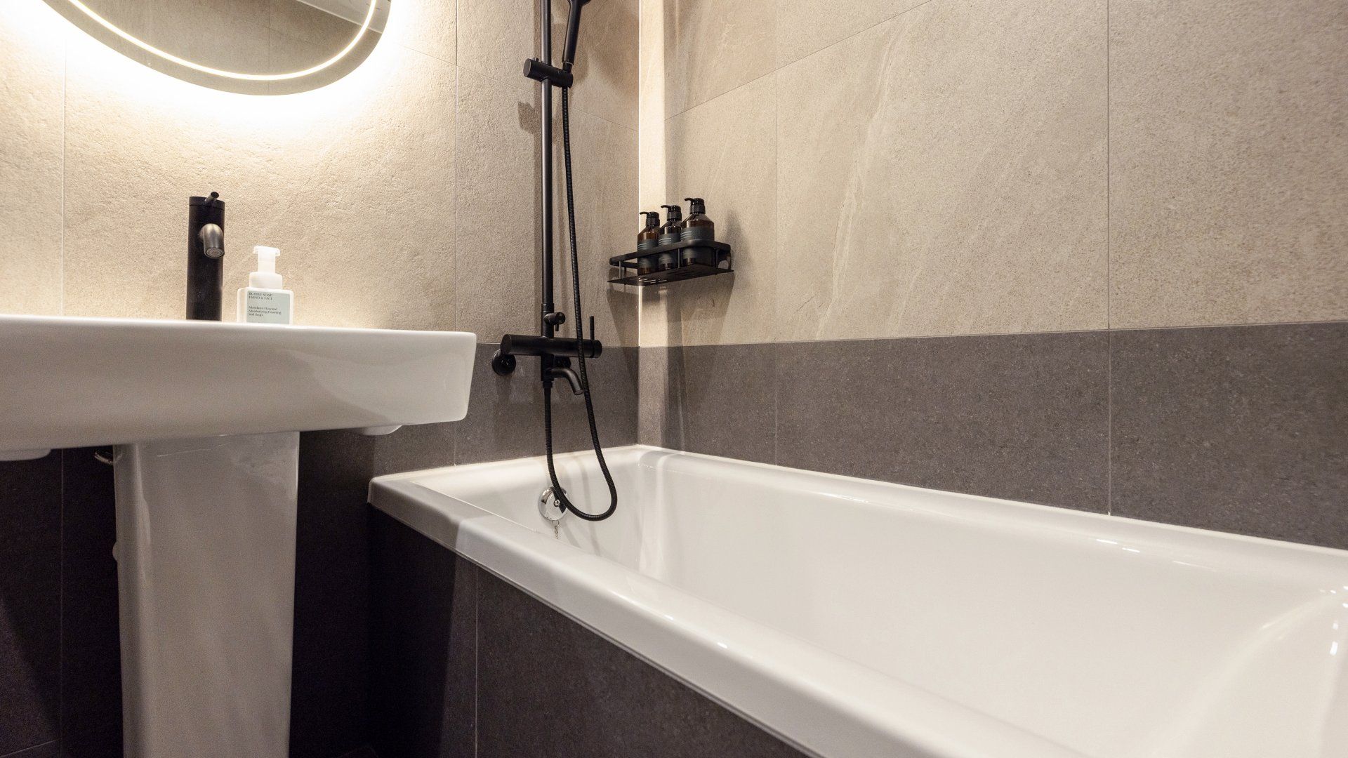 A bathroom with a white bathtub, a sink, and a mirror.