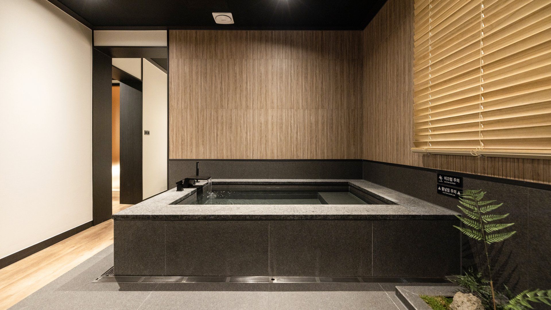 Un bagno moderno con una vasca da bagno indipendente, pannelli in legno e una finestra con persiane.