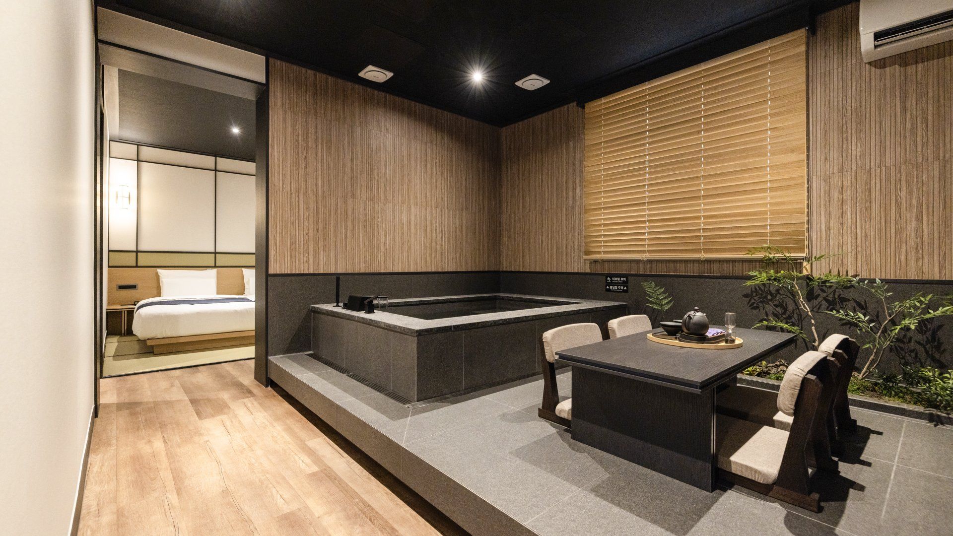 A modern hotel room with a separate dining area, a bathtub, and a small outdoor seating space.