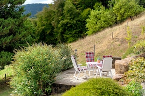 Un patio con mobiliario exterior y vistas a un paisaje selvático.