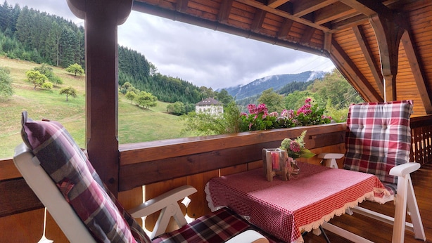 Eine Holzterrasse mit Tisch und Stühlen mit Blick auf eine Berglandschaft.