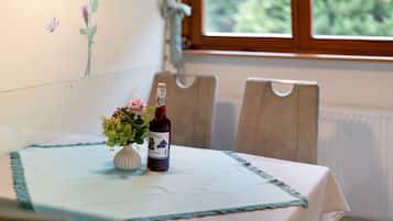 A table with a bottle of wine and a vase of flowers on a tablecloth.