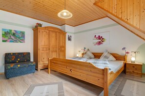 Un dormitorio con una cama y un armario de madera, un sofá y un cuadro en la pared.