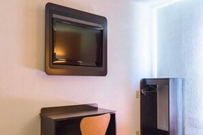 A room with a flat-screen TV mounted on the wall, a wooden chair, and a dark-colored cabinet.