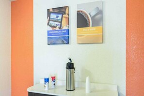 A reception area with a counter, a water bottle, and two posters.