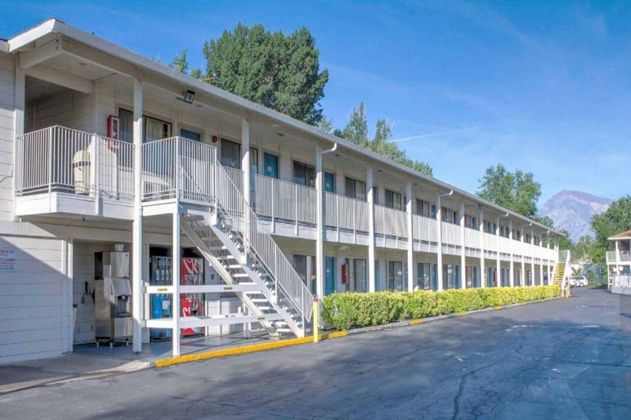 Um motel com escadaria central, várias varandas e estacionamento.