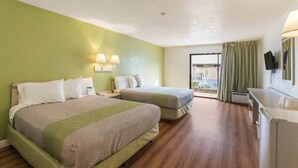 Habitació d'hotel amb dos llits, un escriptori i vista a l'exterior.