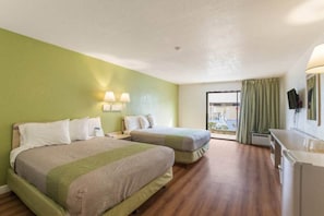 Ein Hotelzimmer mit zwei Betten, einem Schreibtisch und Blick ins Freie.