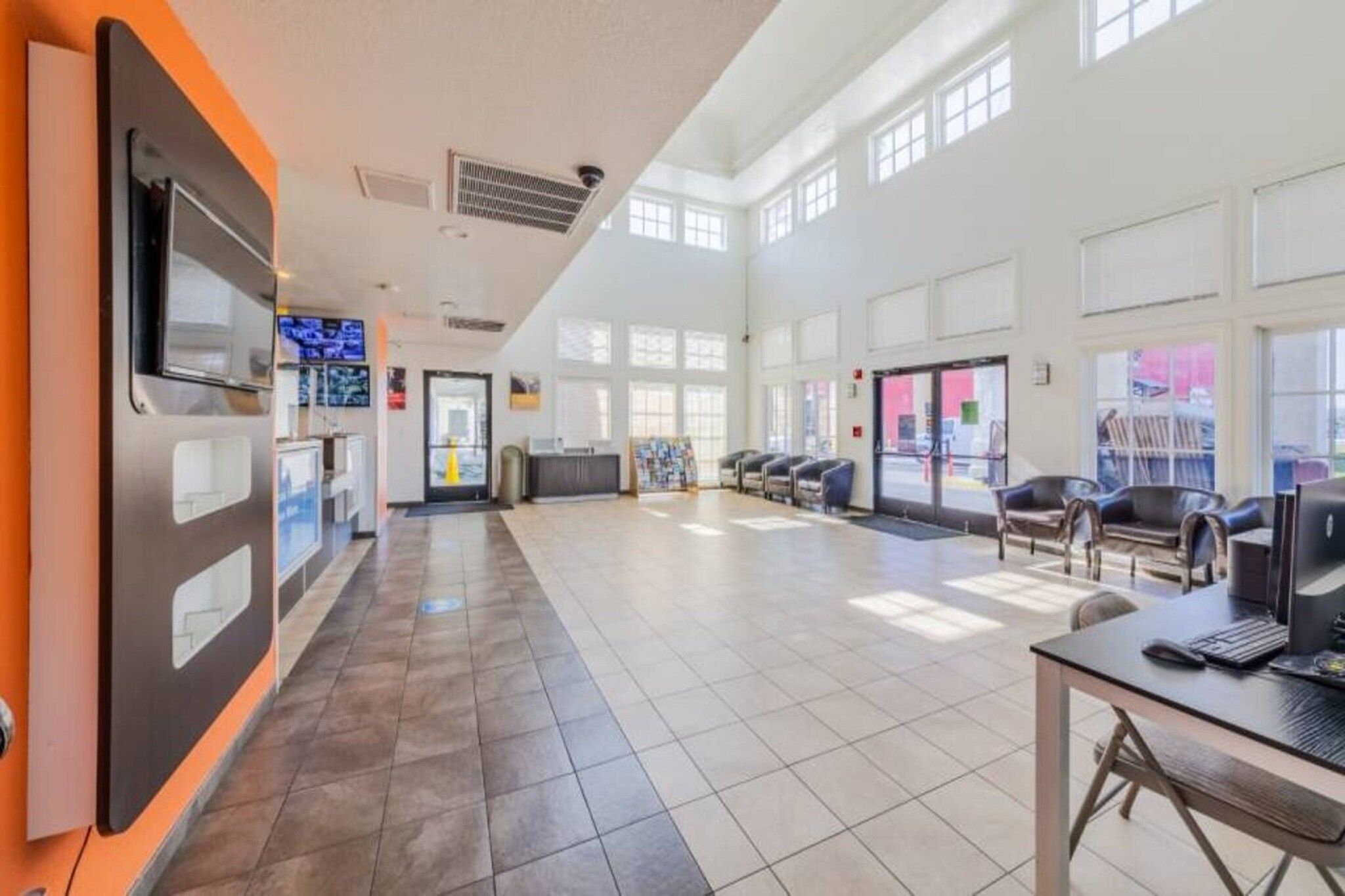 A spacious lobby with a reception desk, seating area, and large windows.