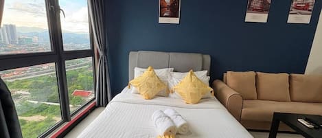 Une chambre d’hôtel avec un grand lit, un canapé et une vue sur le paysage urbain par la fenêtre.