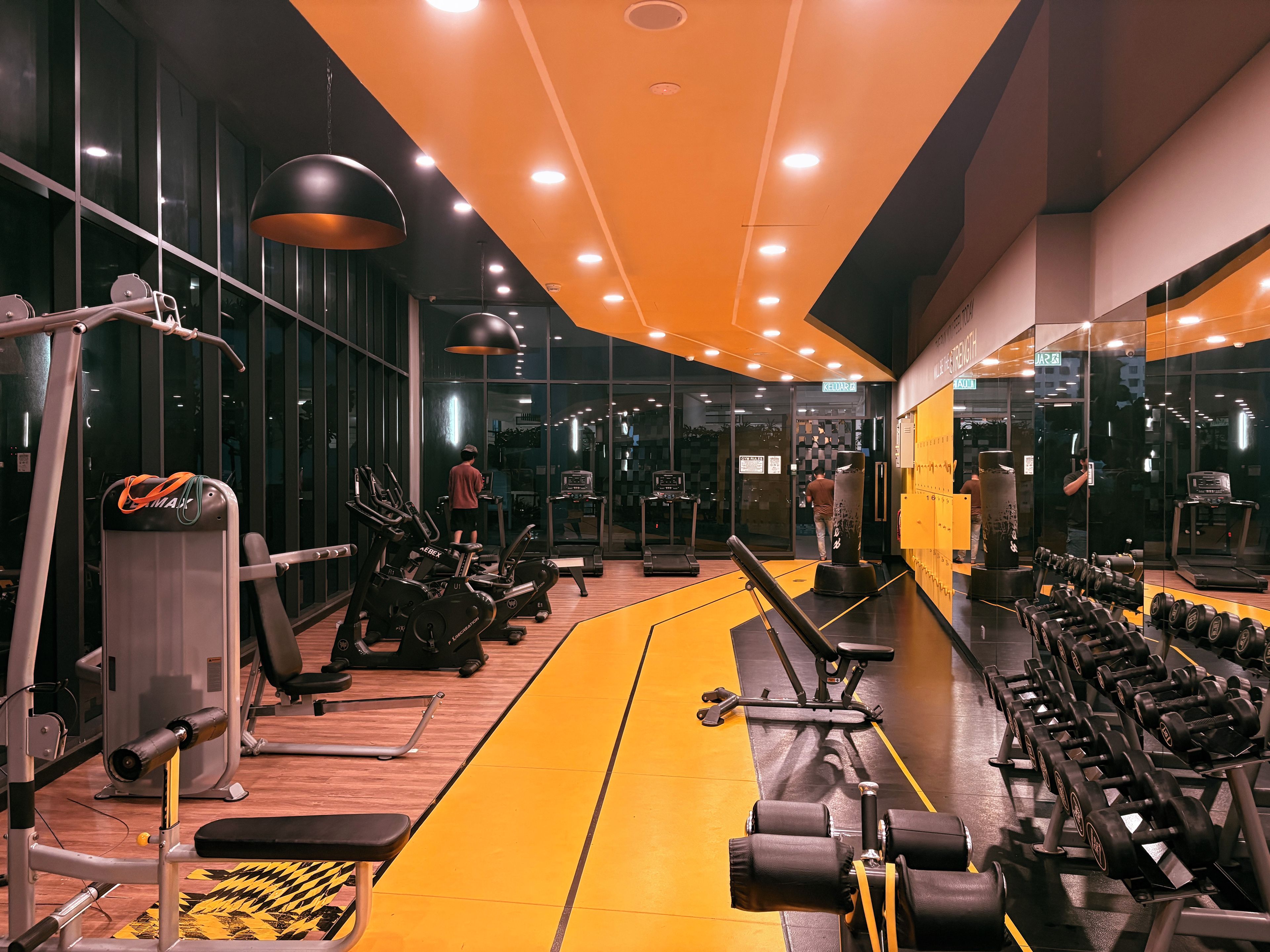 A gym with exercise equipment, a yellow running track, and a mirrored wall.