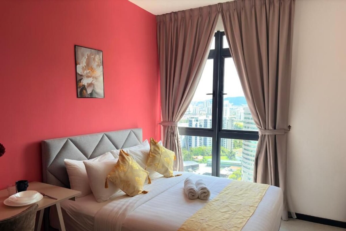 A hotel room with a bed, a window with curtains, a painting on the wall, and a city view.
