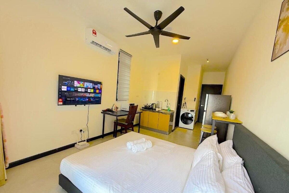 A hotel room with a bed, a desk, a television, an air conditioning unit, and a ceiling fan.