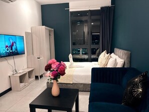 Ein modernes Hotelzimmer mit Bett, Fernseher, Schreibtisch und einer Blumenvase.