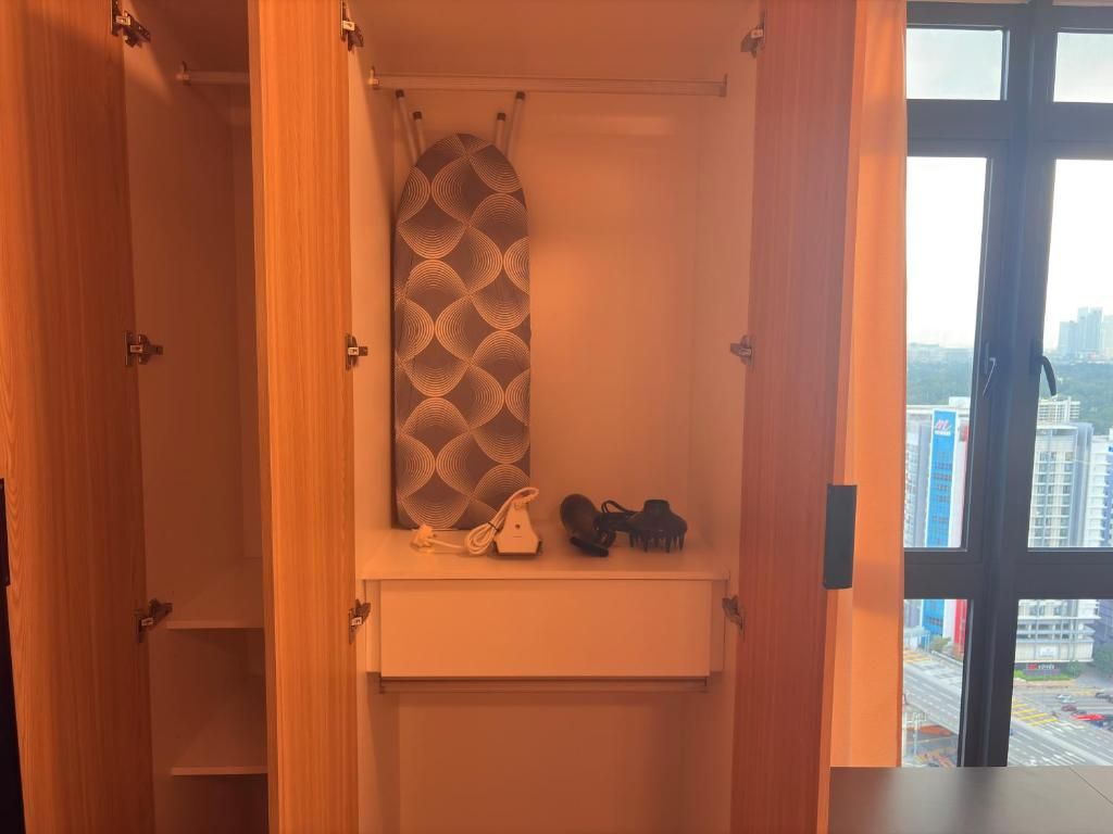 Ein Schrank mit einem gemusterten Duschvorhang, einem Schuhpaar und einem weißen Telefon auf einem Regal.