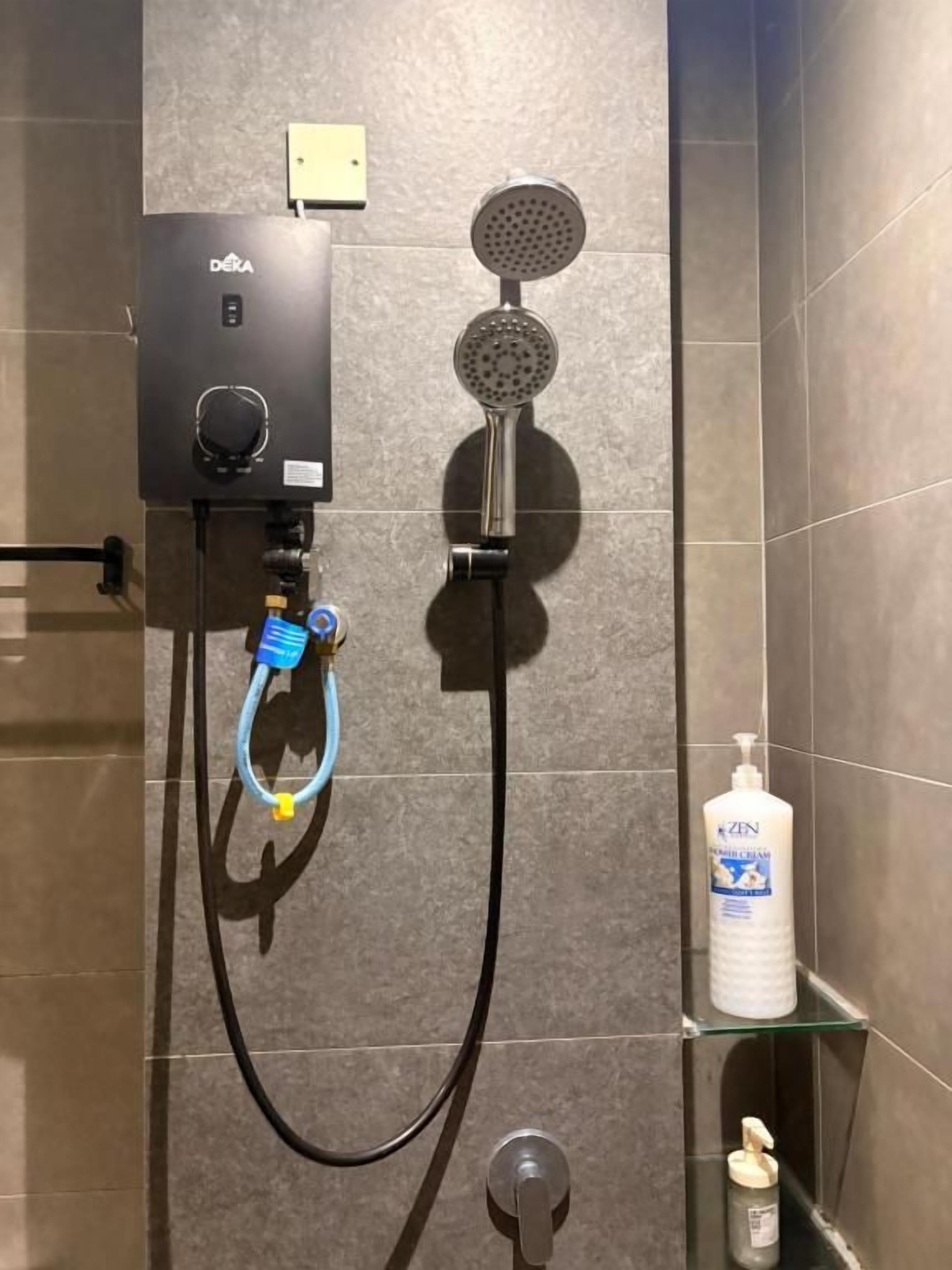 A bathroom with a shower, a control panel, a soap dispenser, and a hand soap bottle.