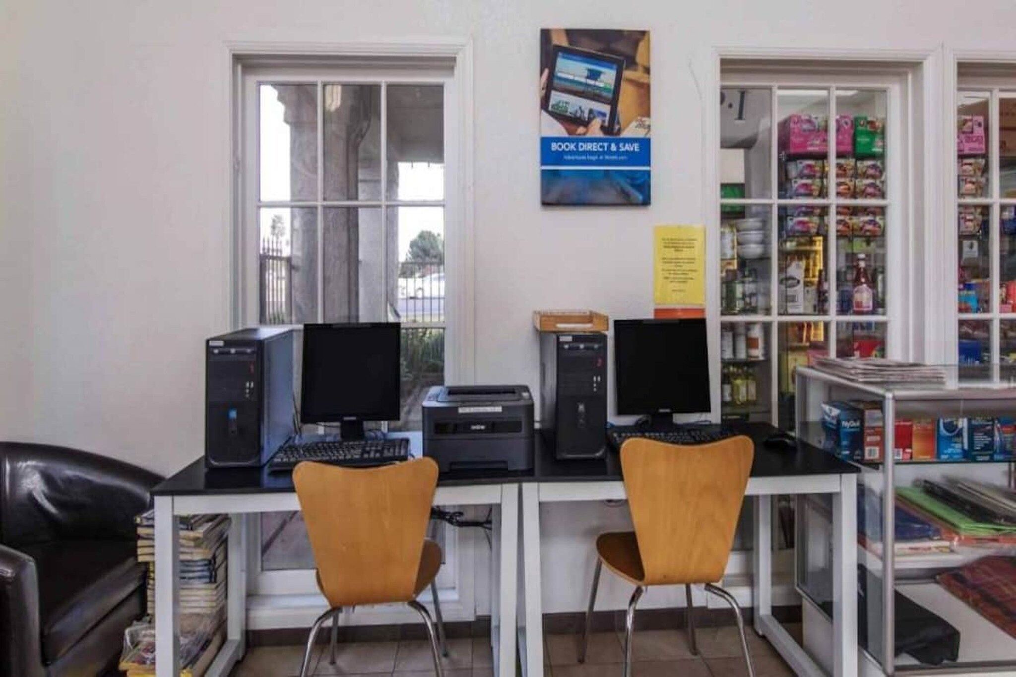Ein Computerraum mit zwei Schreibtischen, Stühlen und einem Bücherregal mit verschiedenen Gegenständen.