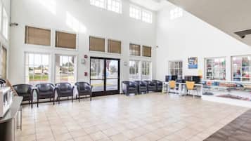 A spacious indoor area with a tiled floor, multiple windows, and a reception desk with chairs.