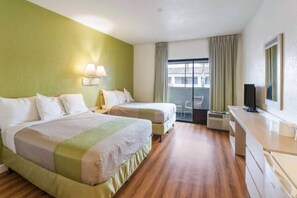 Ett hotellrum med två sängar, ett skrivbord, en tv och en balkong med utsikt.