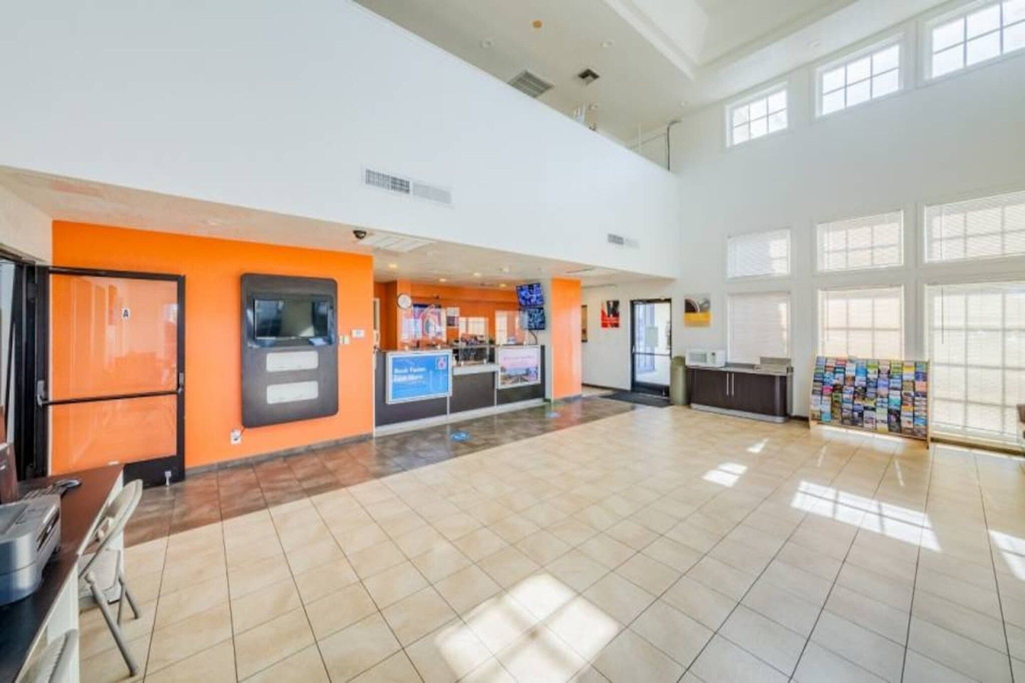 A spacious lobby with a reception desk, a self-service kiosk, and a bulletin board.