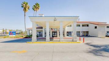 A gas station with a canopy, palm trees, and a building in the background.