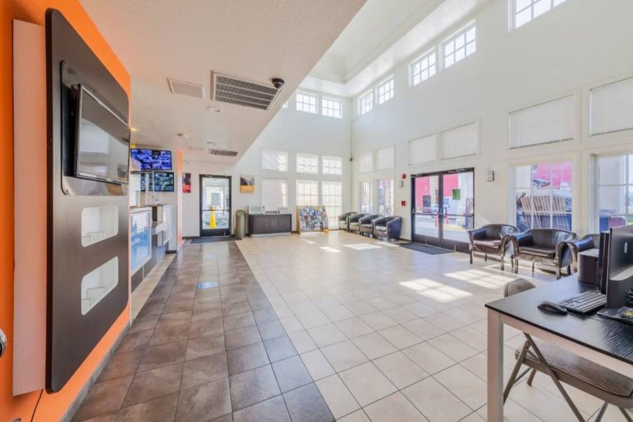 A spacious lobby with a reception desk, seating area, and large windows allowing natural light.