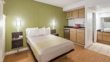 Quarto de hotel com cama, mesas de cabeceira, cozinha compacta e banheiro.